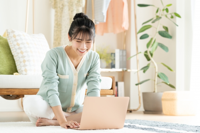 床に座ってパソコンを開いてる女性